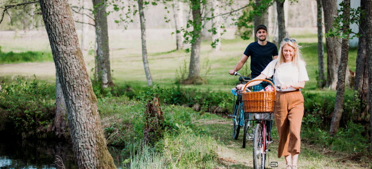 Två personer med cyklar som går i en skog. 