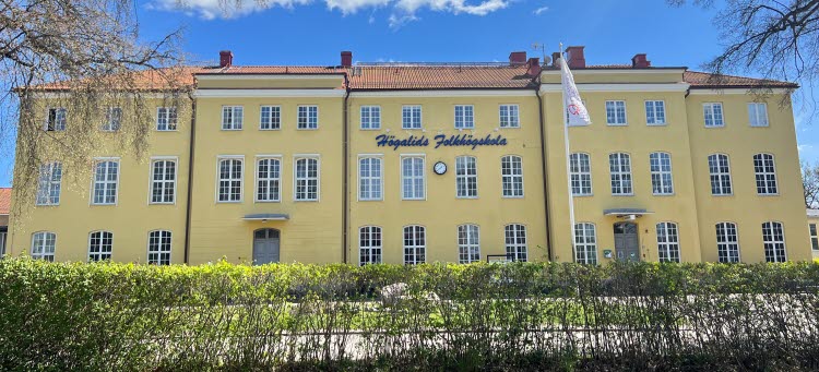 Bild på Högalids folkhögskola rakt framifrån. En gul stenbyggnad. 