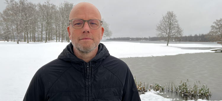 Patrik Tagesson står i snöbeklätt landskap och vattnet på ena sidan av sig.