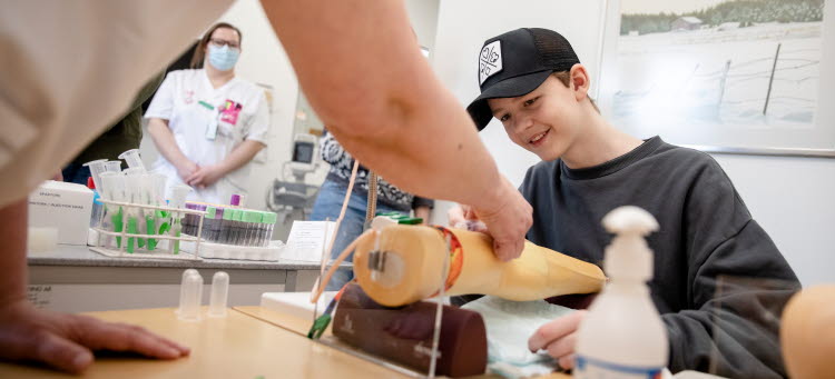 En ungdom blir visad hur man tar blodprov.